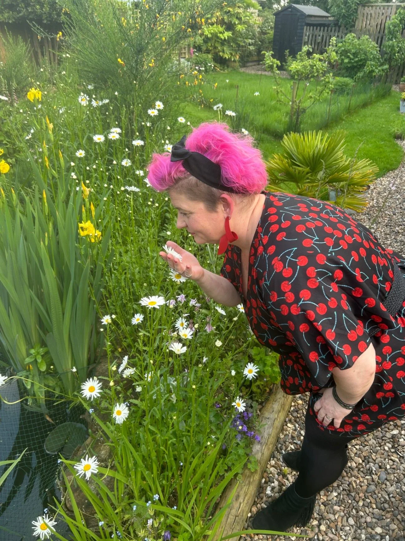 Belinda Warburton pausing beside flowers in her garden.